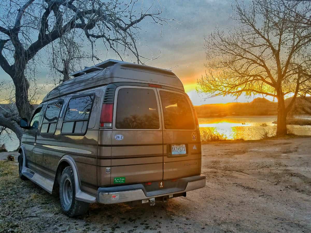 Van parked at a State Park campground with a beautiful sunset in the background