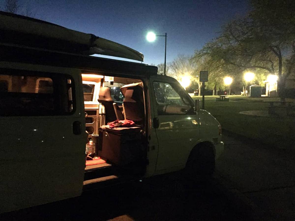 A camper van parked at a highway rest area. Rest stops are another great option for sleeping in your car