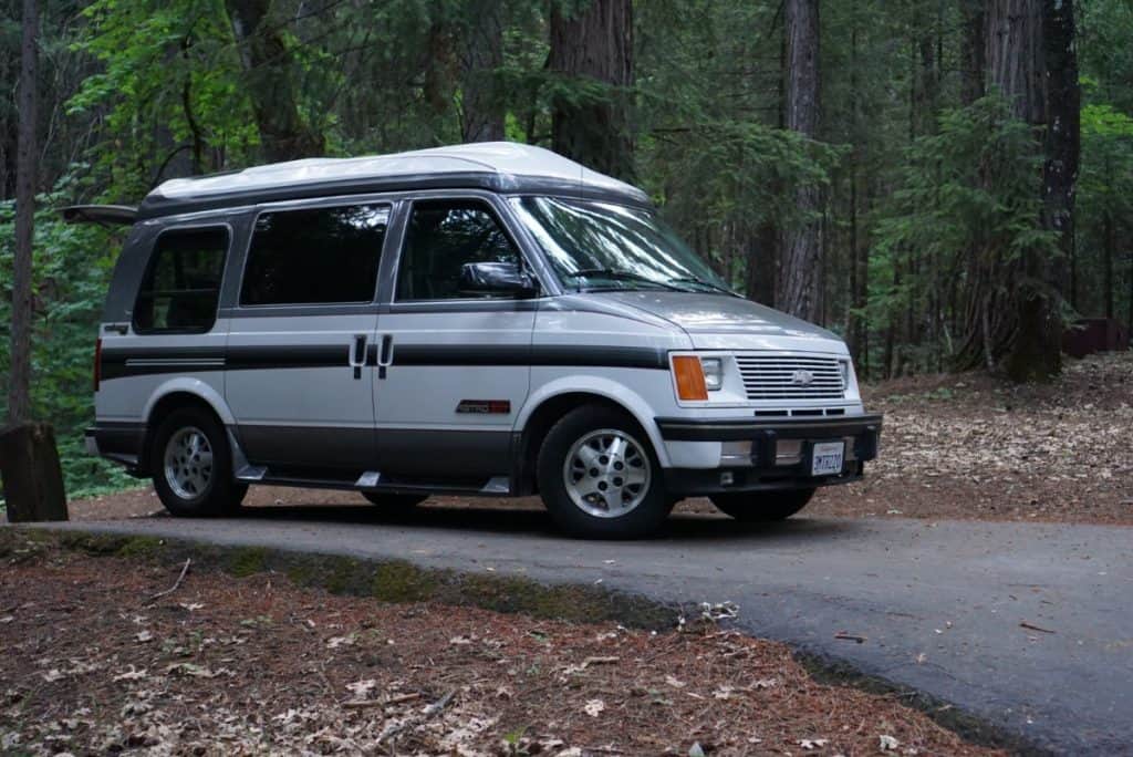 A van sits in the middle of the woods.