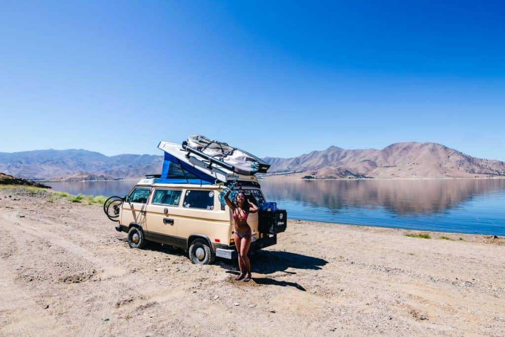 woman wearing a bathing suit stands outside of van