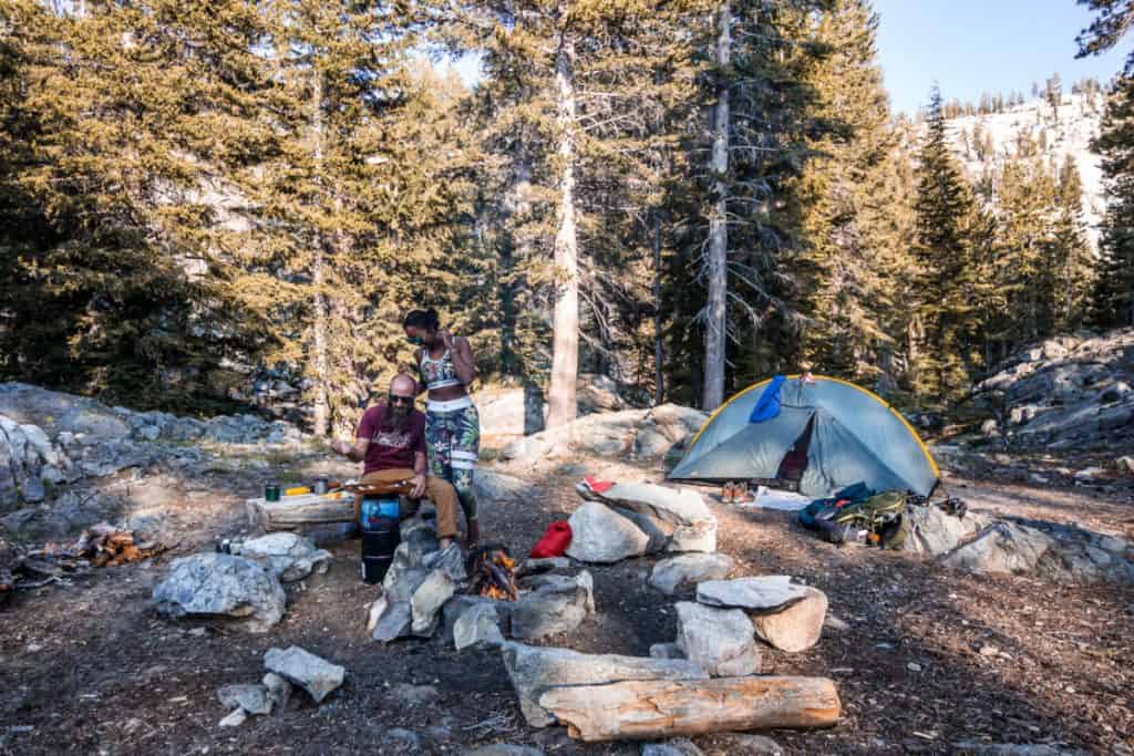 man and woman enjoy each other at campsite in the woods