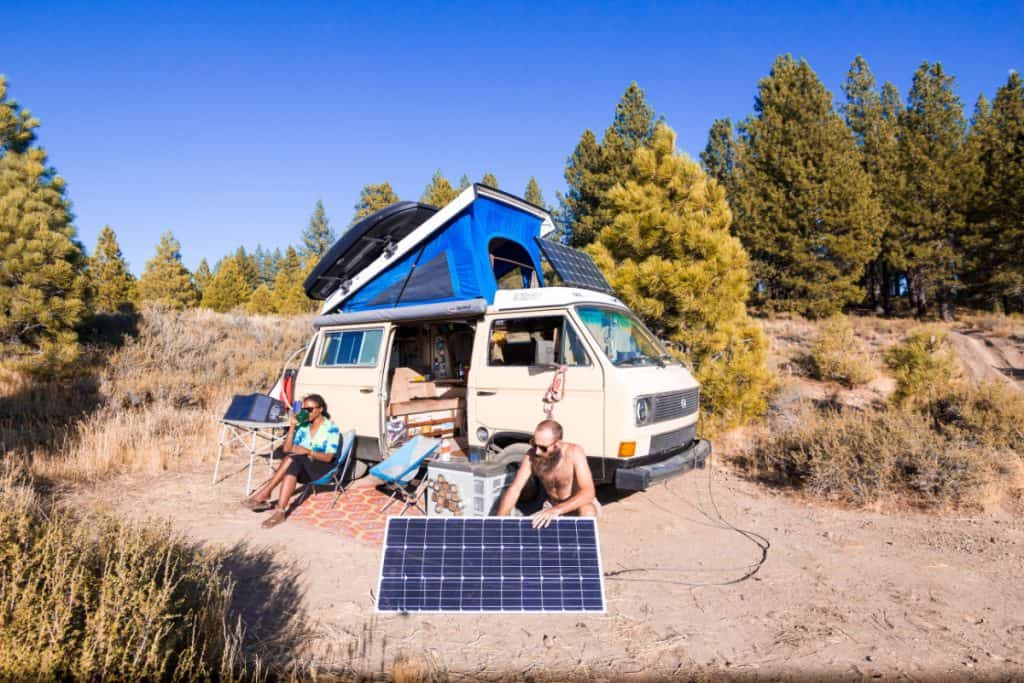 man sets up solar panel outside van