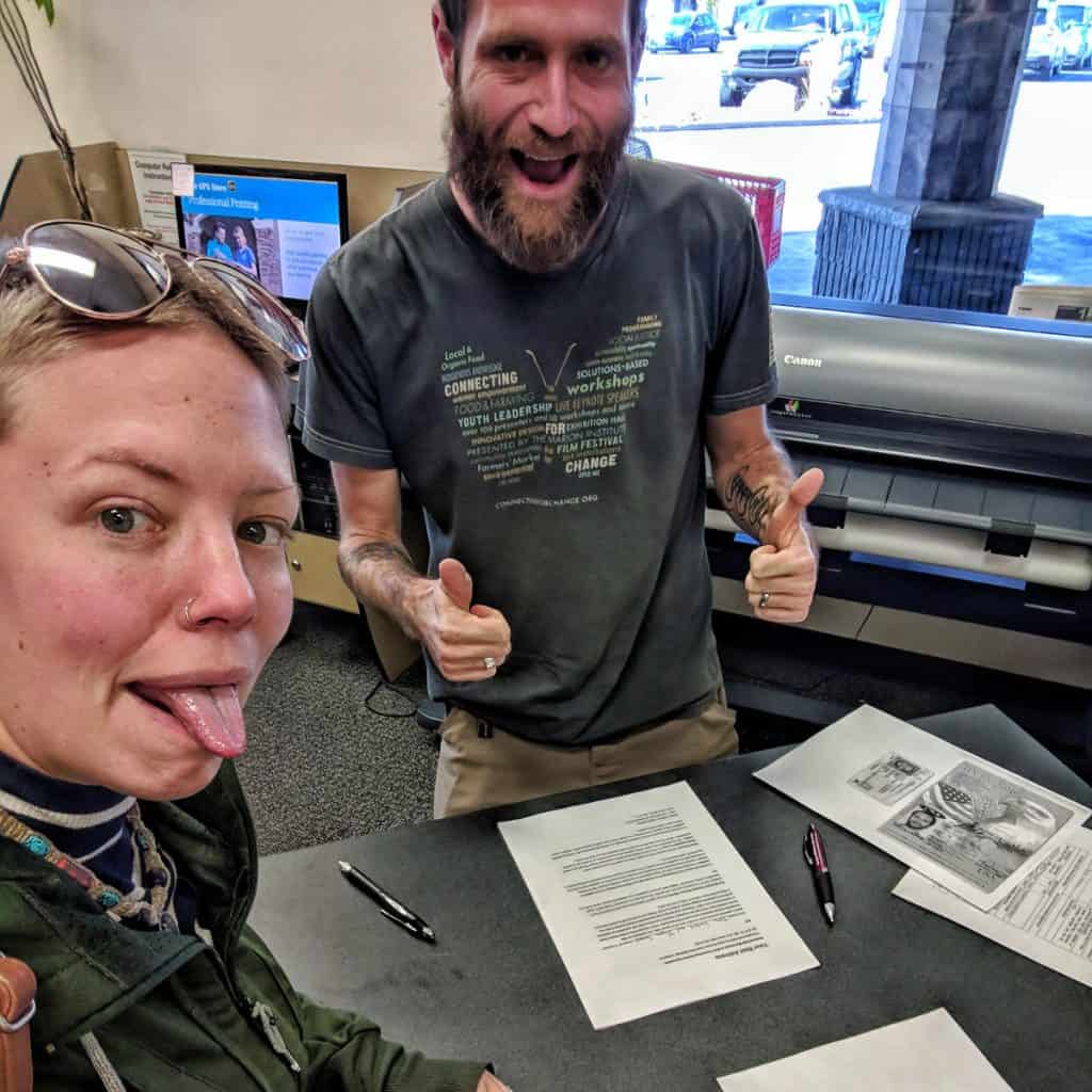 Man and woman signing paperwork with thumbs up