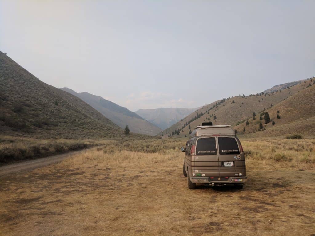 Van parked in a valley, looking out on some beautiful mountains