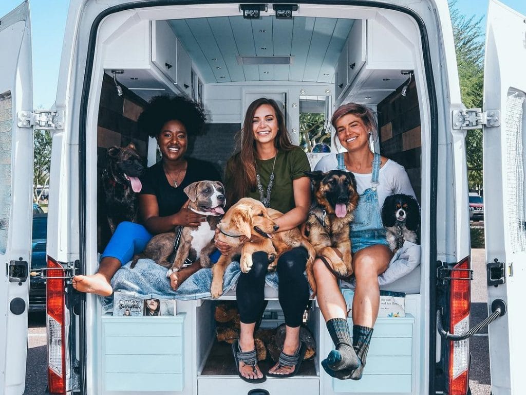 Three women looking out the back of a campervan