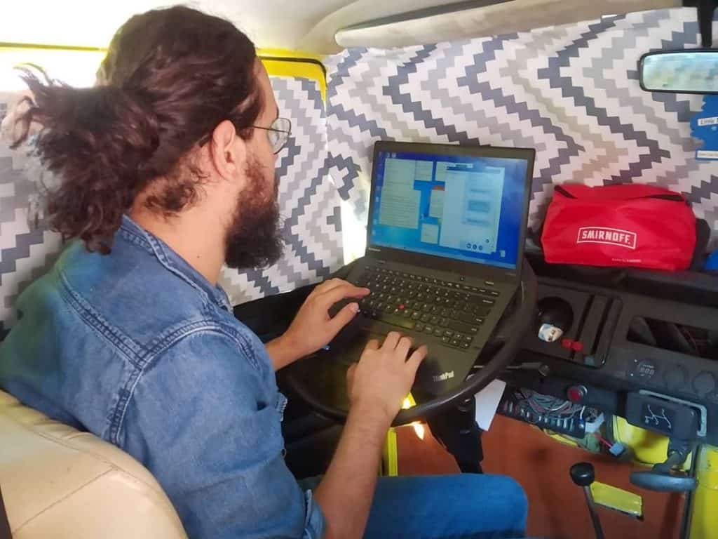 guy working on laptop on steering wheel