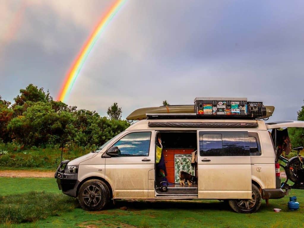 van camped with a rainbow behind it