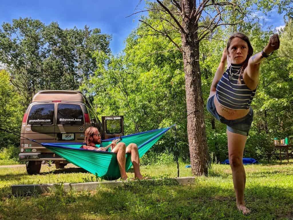 woman doing yoga man in hammock van camped behind