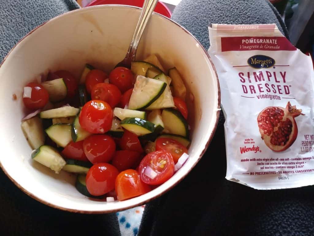 A bowl of veggies with a side of pomegranate seeds