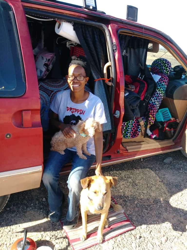 Crystal poses with two dogs while sitting on the edge of her red minivan