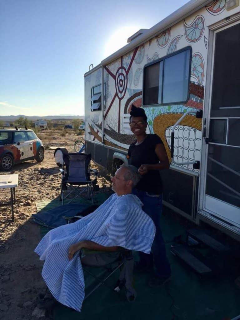 Crystal does an older man's hair outside of an RV