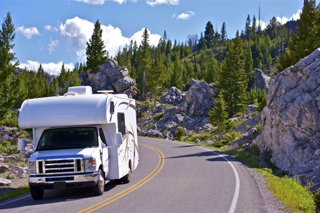 class c rv driving down a road in the alpine mountains