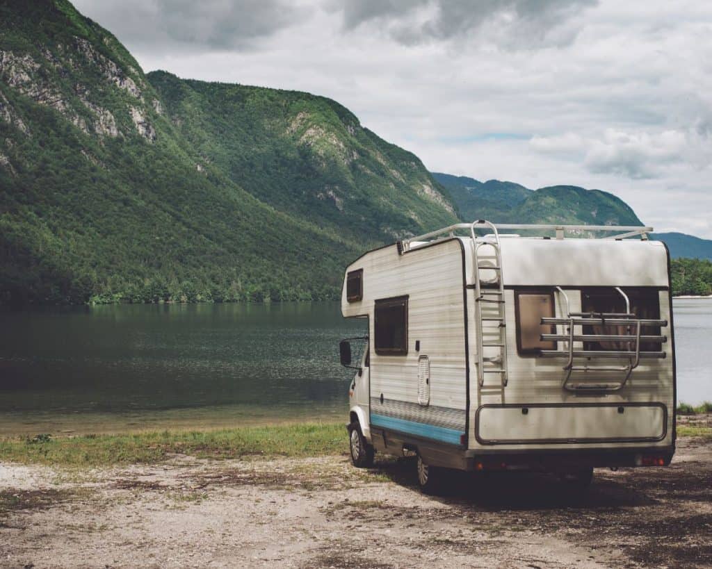 older class c rv parked by a lake shore