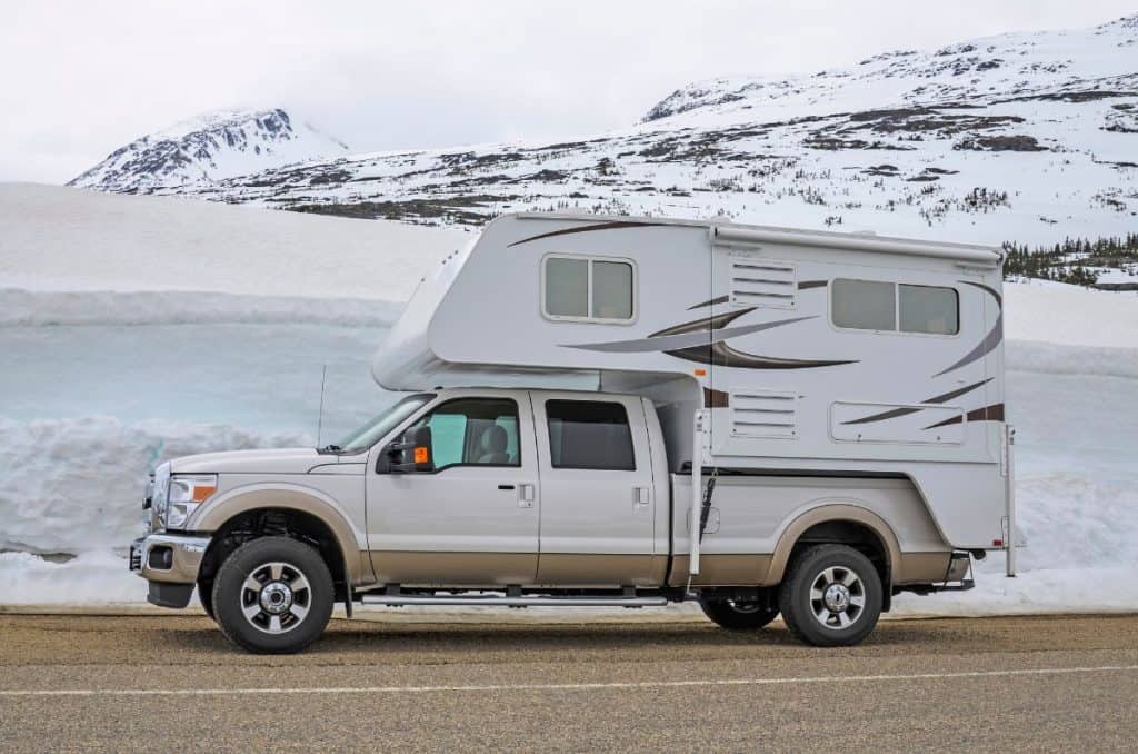 truck camper driving down a snowy road