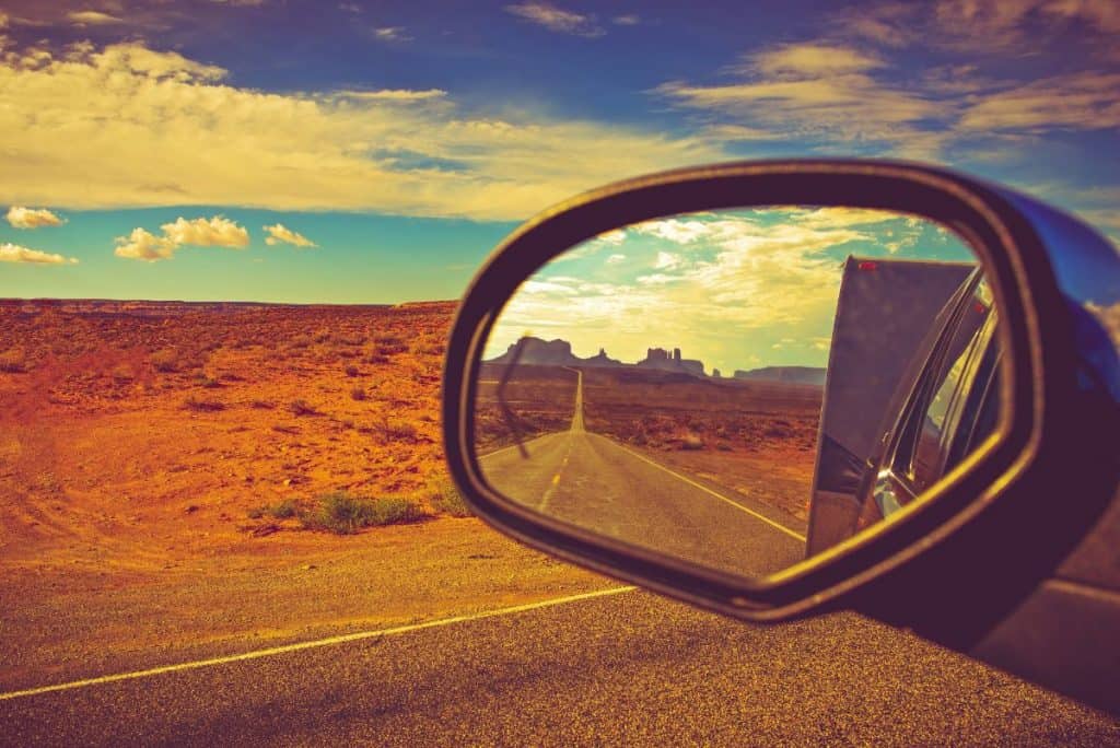 the road seen through the rearview mirror of a truck towing an rv