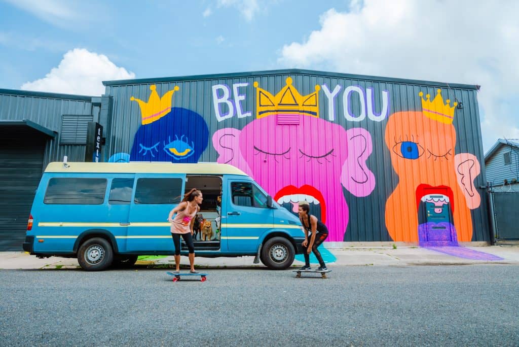 Abi & Nat skateboard in front of their van.