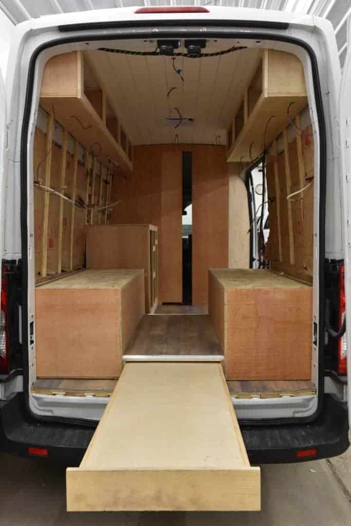 An interior shot of the van mid-build, filled with framed walls and the base of the couches.