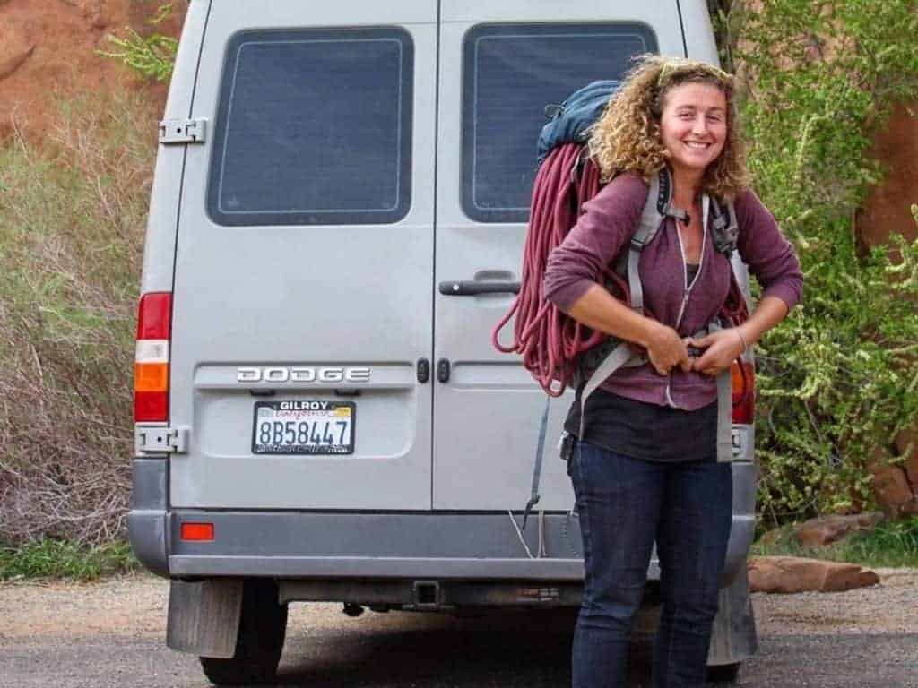 Kaya puts on a backpack behind her van.