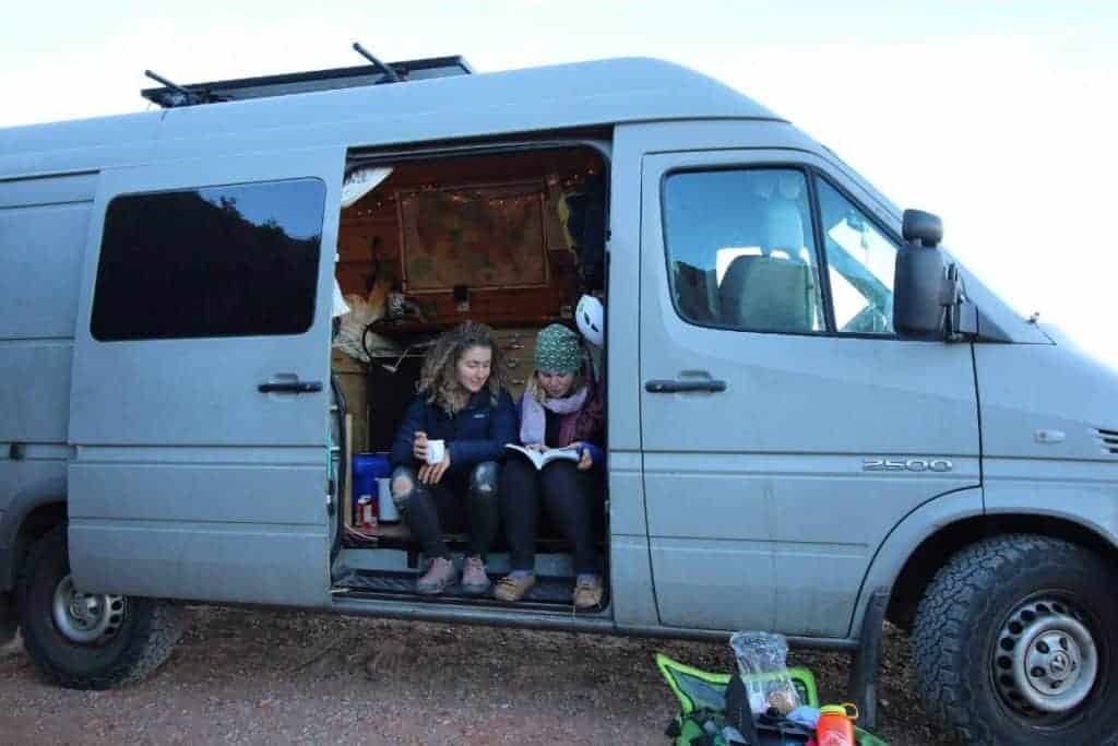 Kaya and a friend sit out her side door look through a book.