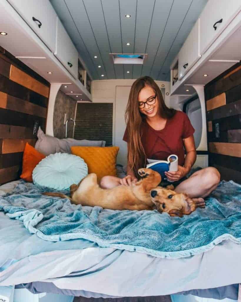 Sydney sits in bed reading, petting her dog Ella.