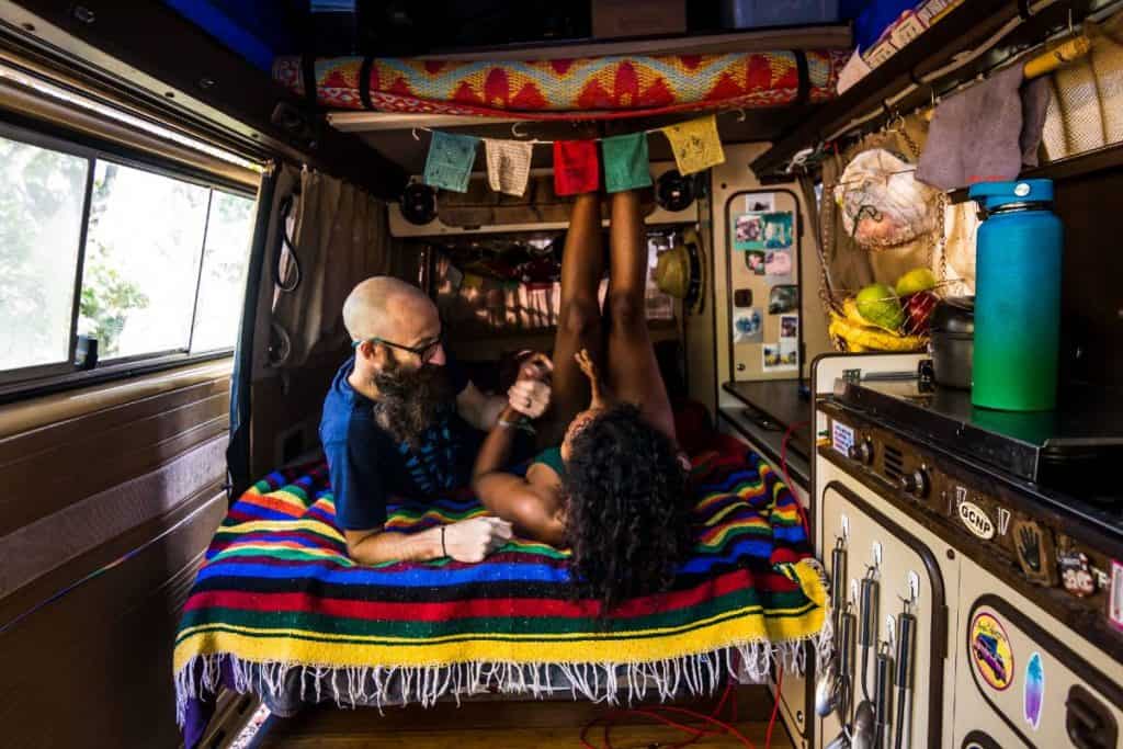 Dustin and Noami clasp hands while lying in bed.