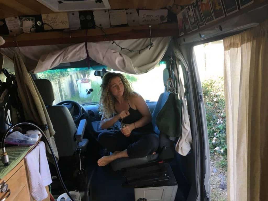 Kaya sits in her swiveled passenger seat, grinding coffee beans.