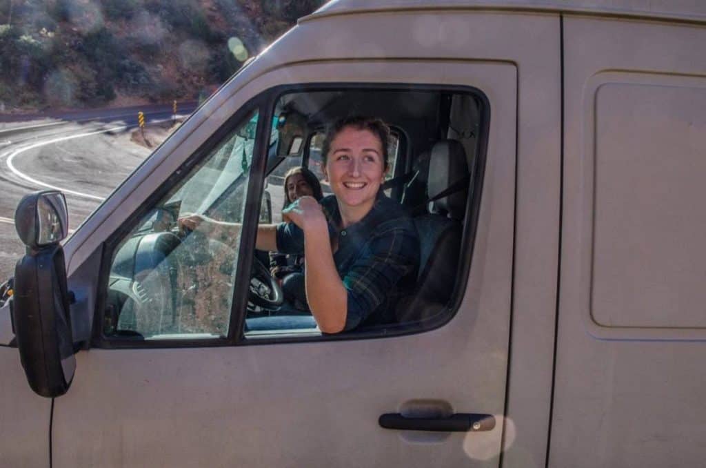 Kaya looks out the driver's window smiling.