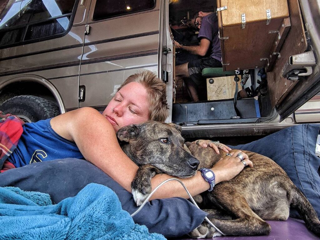 Jayme cuddles with her dog Nymeria out the van's side doors.