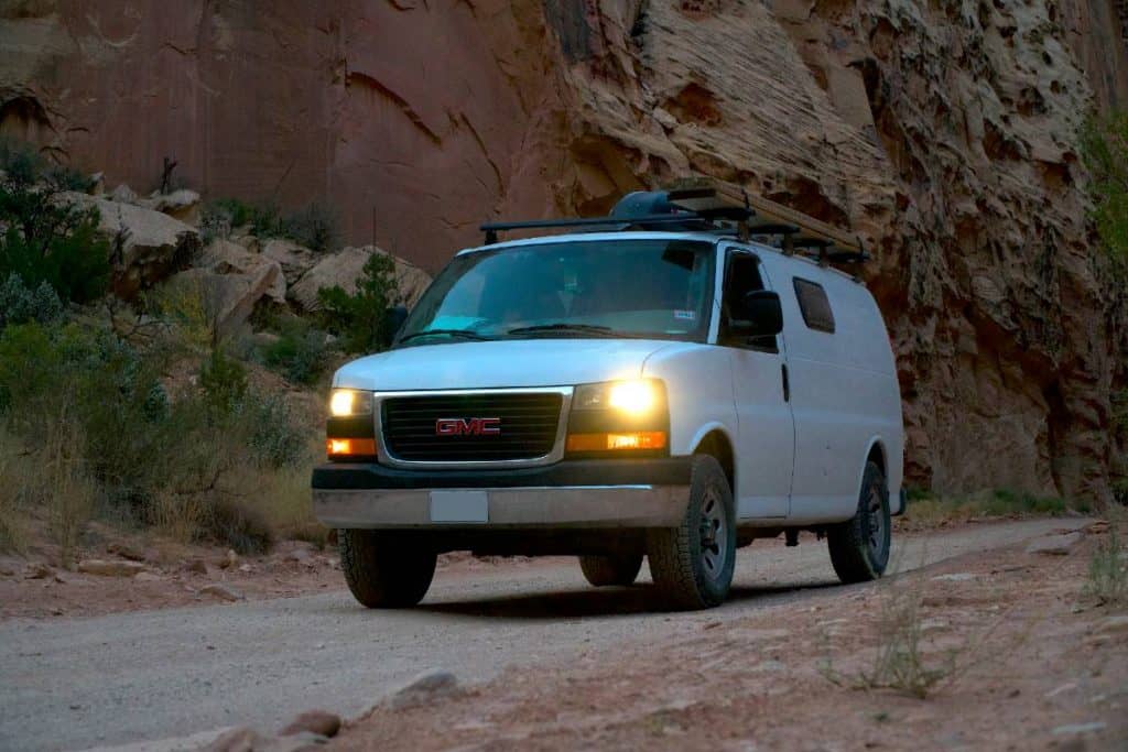 The van drives next to a cliff wall.