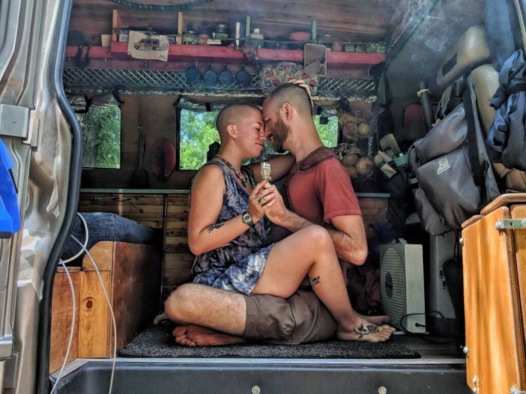 Jayme sits in John's lap in the van and they hold a smoking sage bundle.