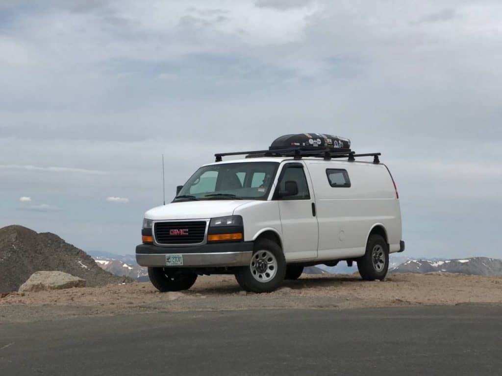 The van is parked on a ridge. You can see the ocean in the background.