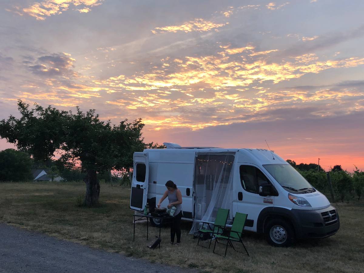 Cooking dinner outside the dodge promaster with a sunset in the background