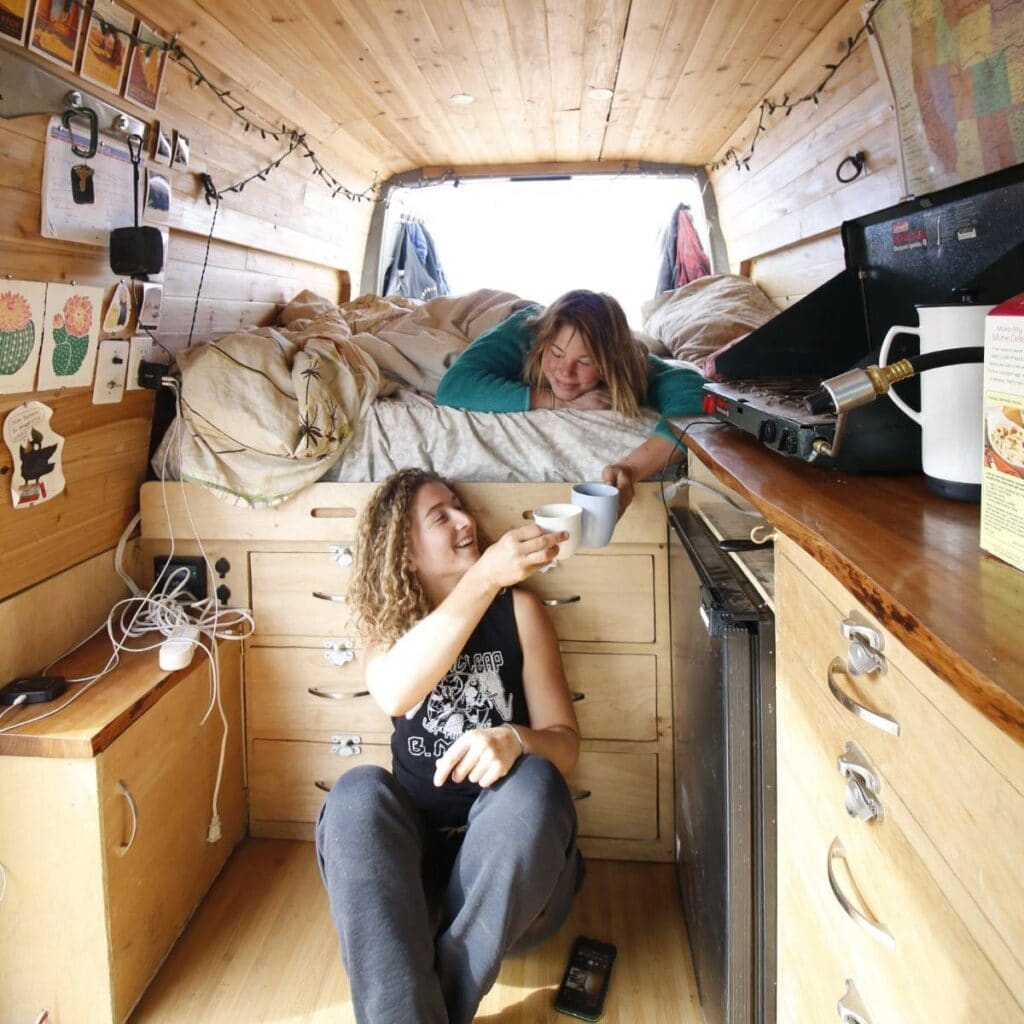 Two women sharing coffee inside a Sprinter van