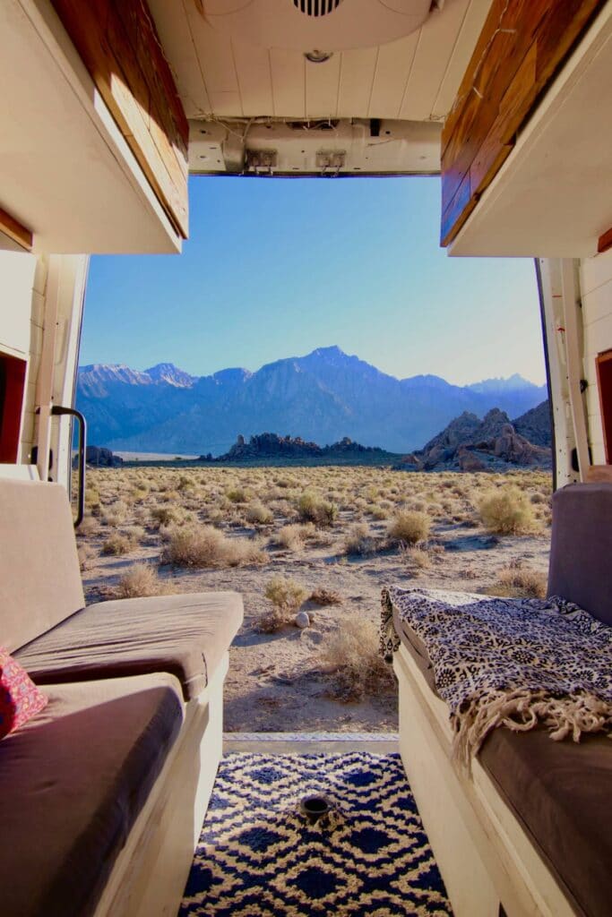 Looking out the back doors of a Nisaan NV2500 onto the mountainous desert