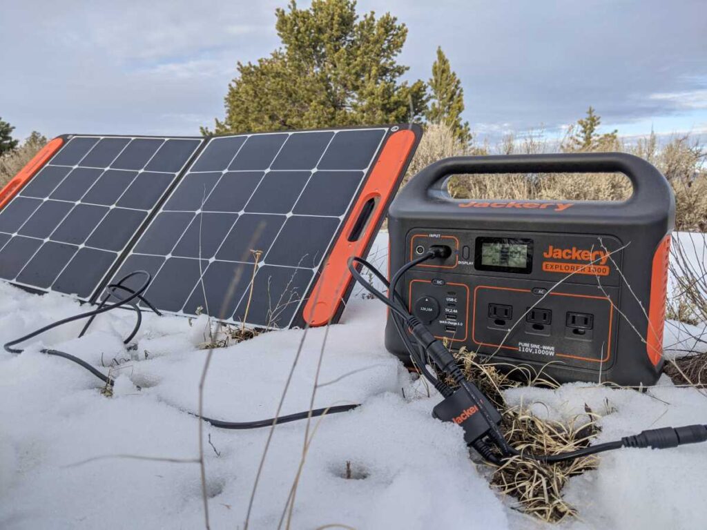 The Jackery 1000 on the snowy ground with a solar panel right next to it