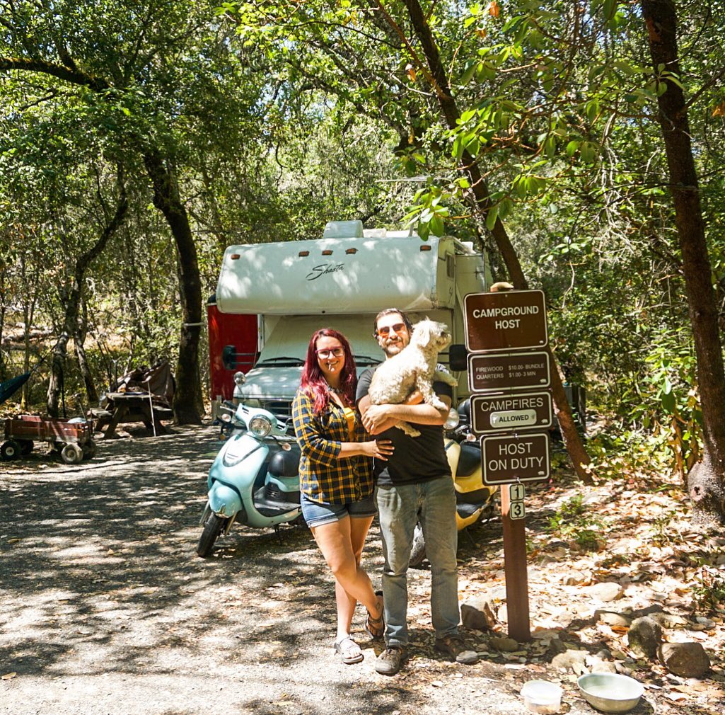 Couple standing by camp host sign