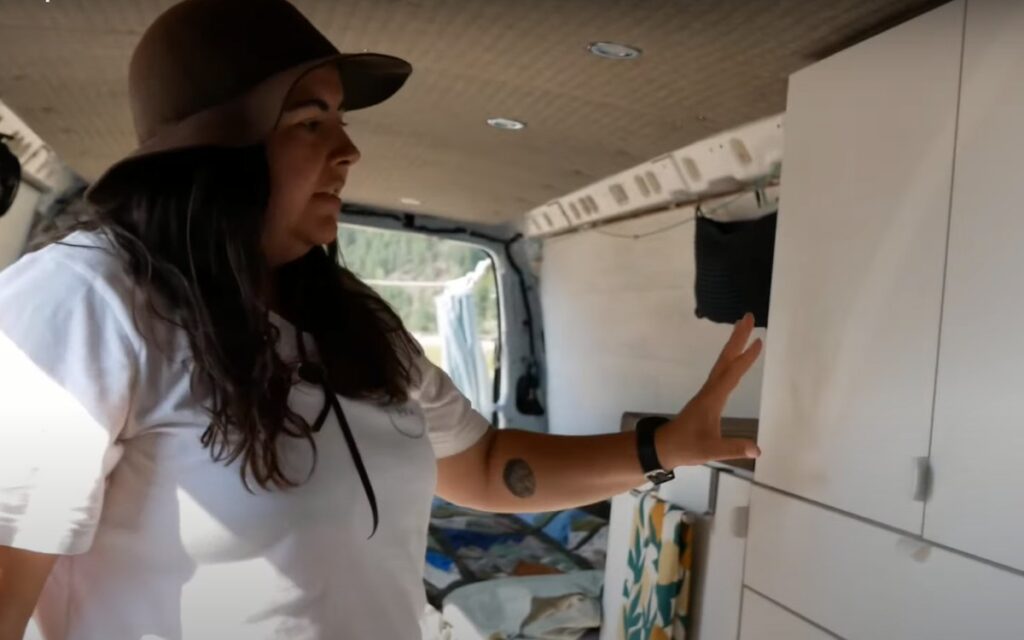 @paddlethepnw Woman showing the cabinet inside her chevy express camper van