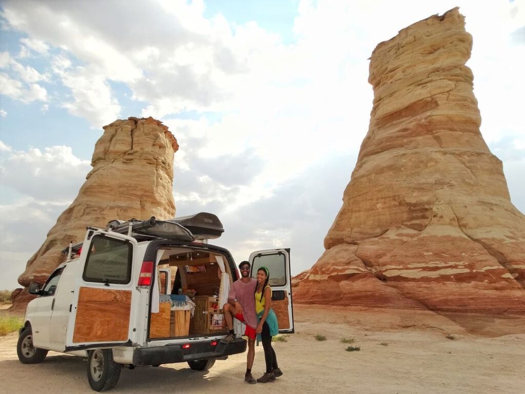 @r.m.travels Young couple standing at the back of a chevy express camper van