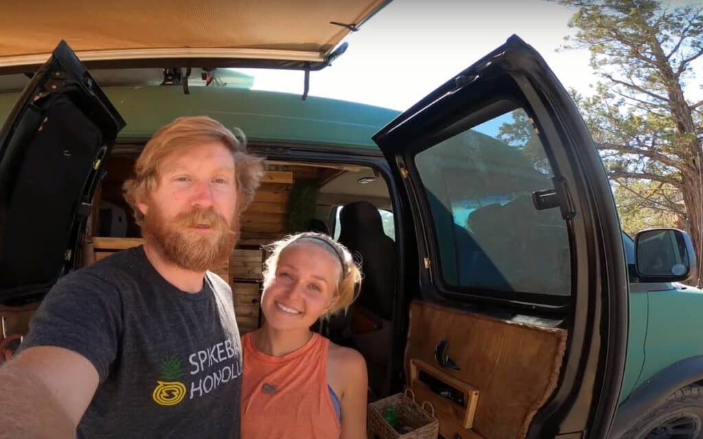 Billy and Sarah standing next to their chevy express camper van, chevy express van life