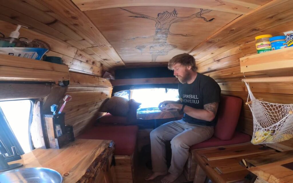 Billy sitting in front of a mini table inside his chevy express camper van