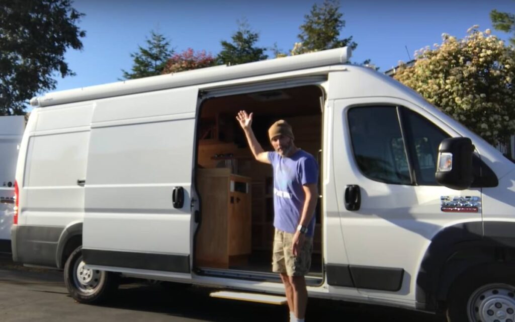 Man standing by the door of his ram promaster camper van