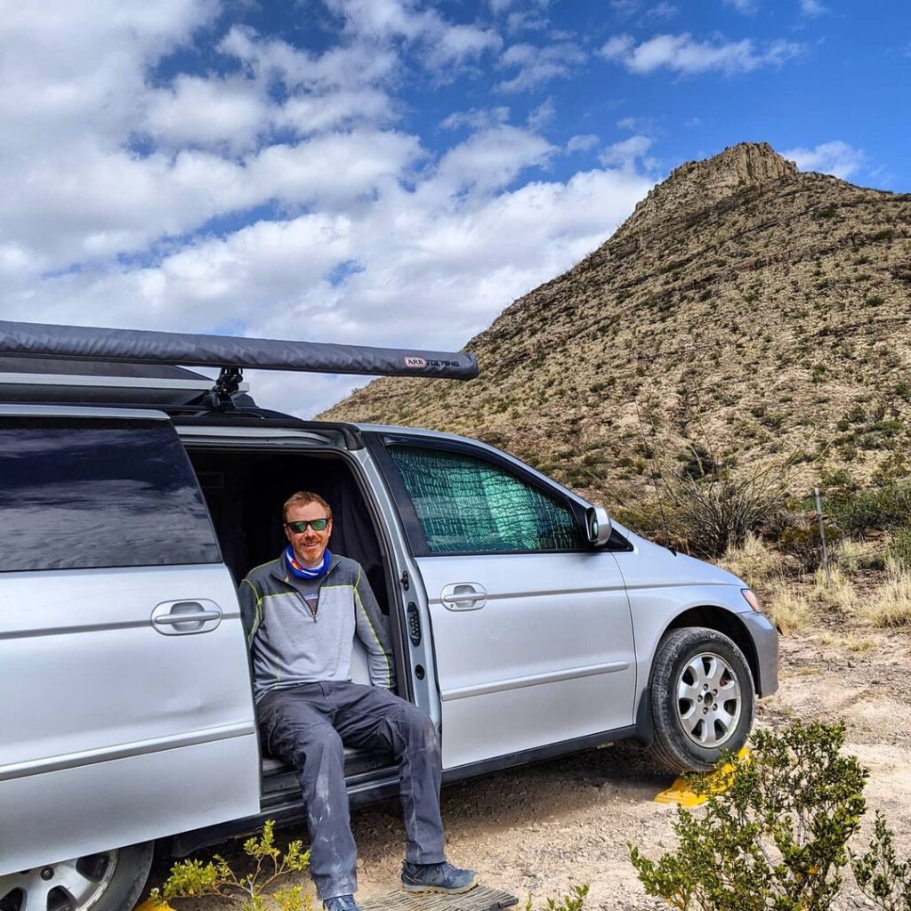 @jay.moyes Man sitting at the open door of a converted minivan