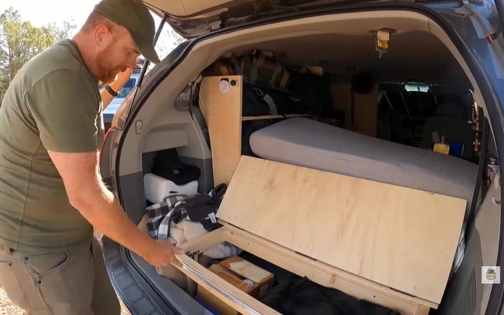 Josh showing the interior of his minivan camper from the back