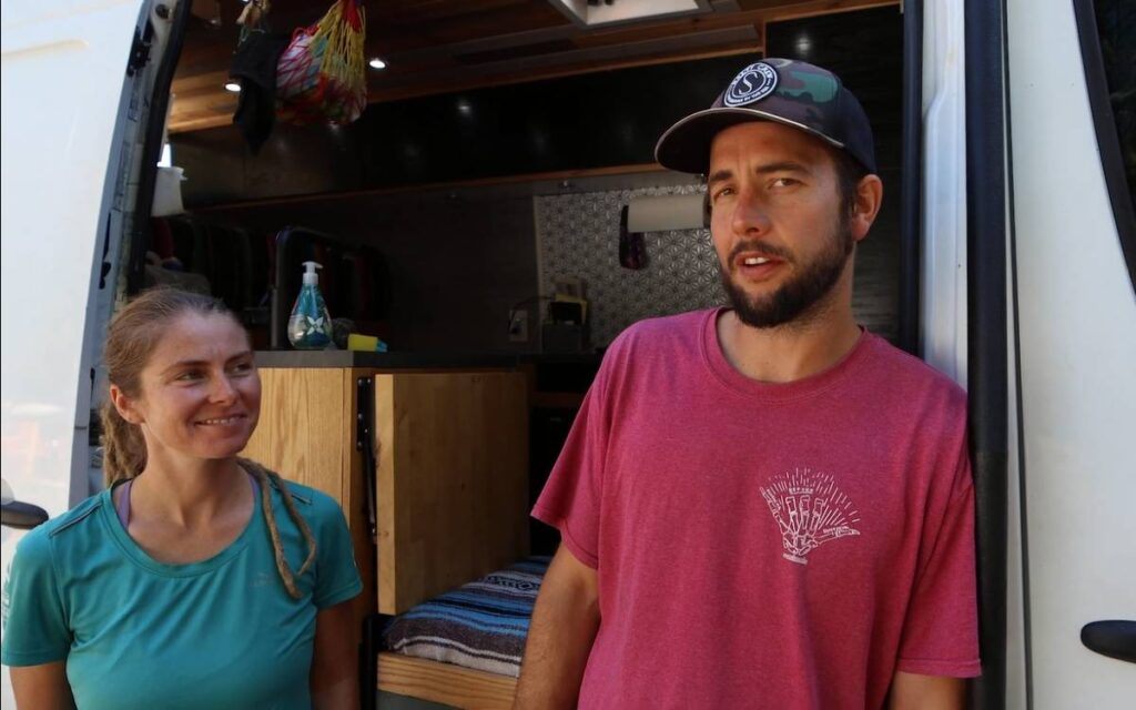 @vankookz couple standing next to their camper van, sharing their sprinter van build experience