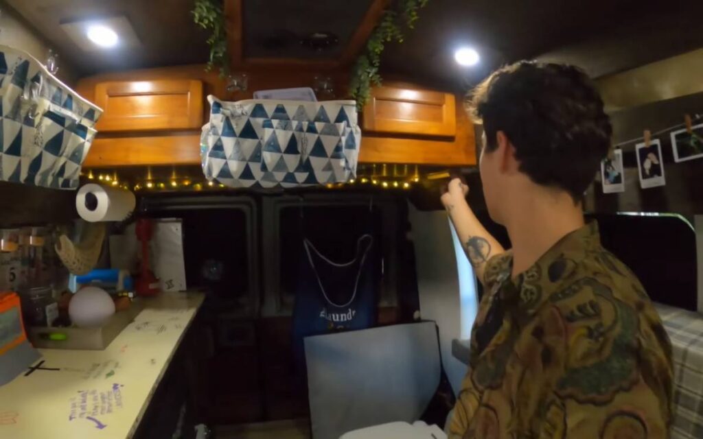 @braxton_lynn_youtube man showing the interior of his ford econoline camper van