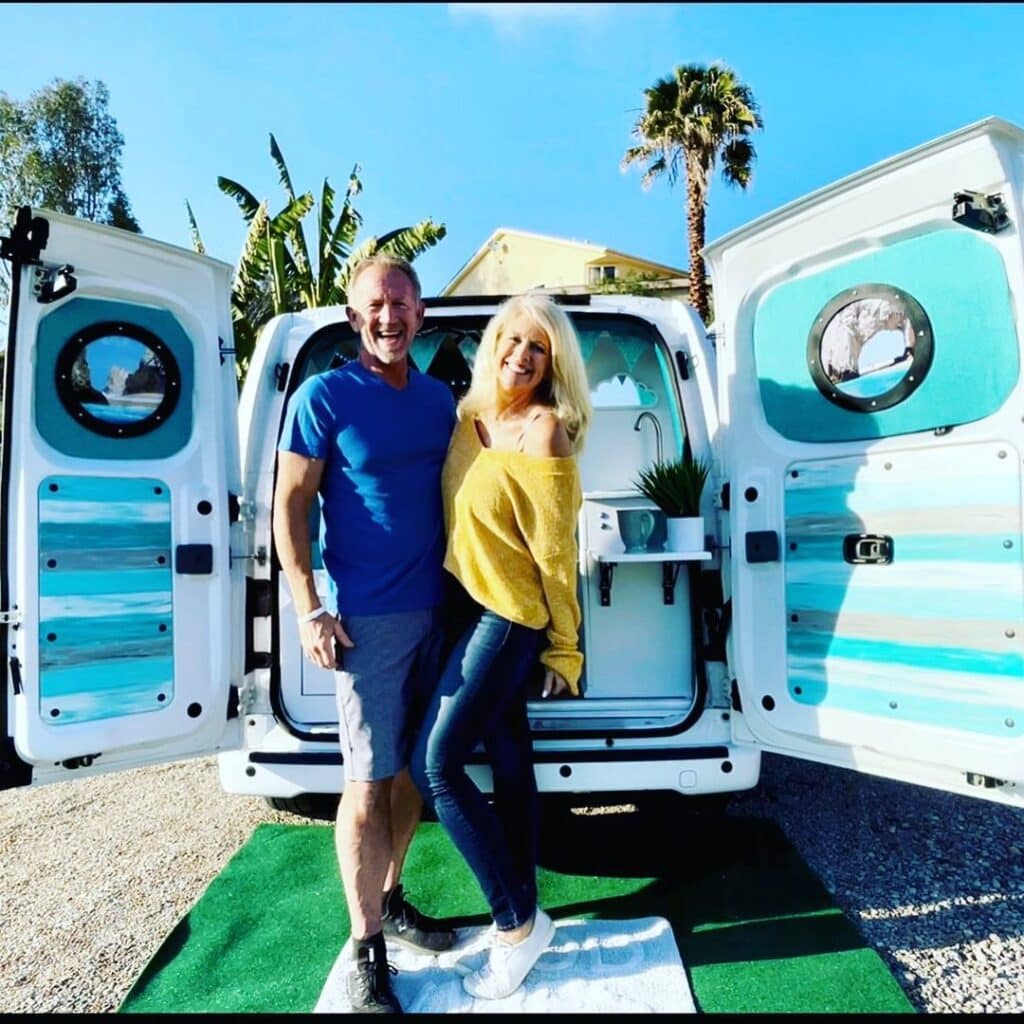 @happilytravelingeverafter Couple posing next to their nissan nv200 camper