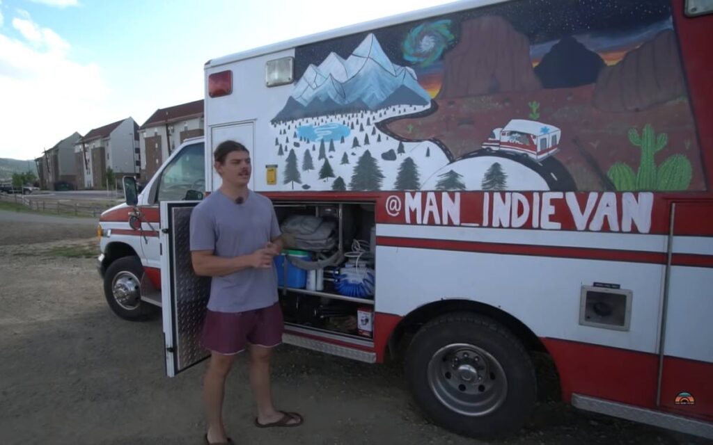 @man_indievan Young man standing next to a converted ambulance with painted exterior