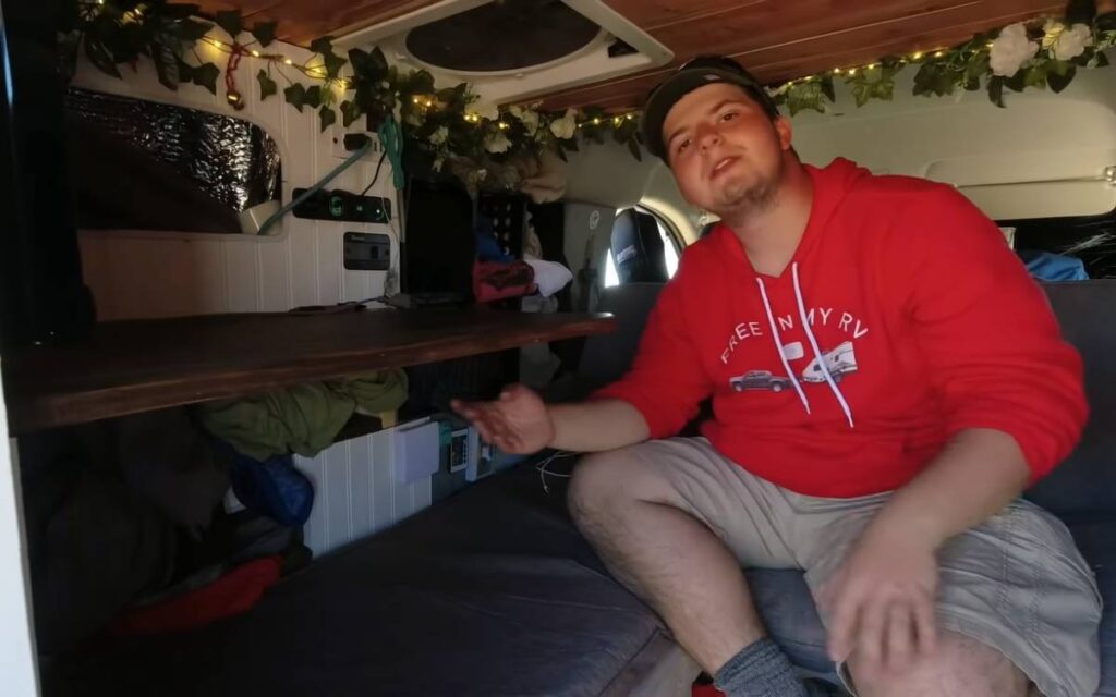 Cam sitting in a sofa inside his nissan nv200 campervan