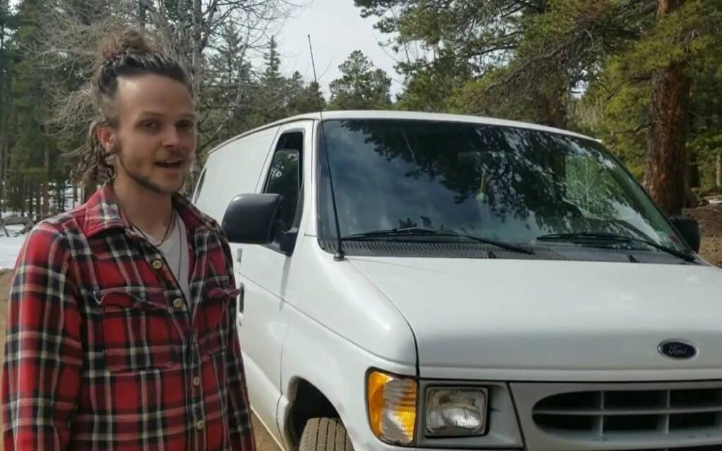 Kaia Fox standing next to his white ford e series camper van