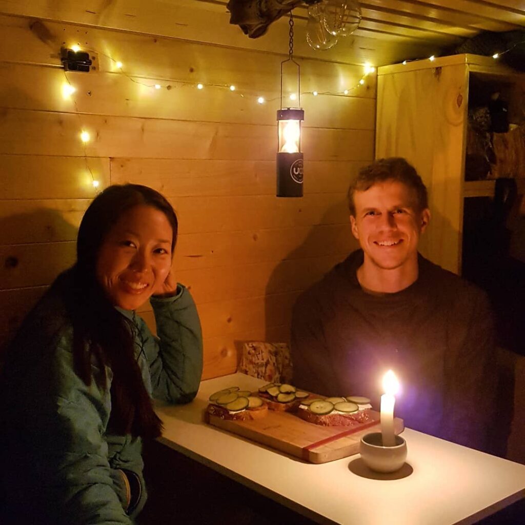 @roadtopitches Couple sitting at the table having a romantic dinner inside their box truck camper